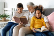 © NDABCREATIVITY - Multiethnic family. Grandparent teaching children to read for school