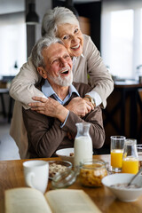 Wall Mural - Smiling senior couple sitting outside at sunset