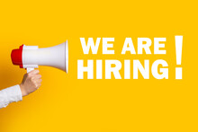 Female Hand Holds A Megaphone On A Yellow Background, Added The Inscription We Are Hiring
