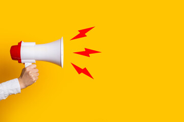 female hand holds a megaphone on a yellow background, added picture sound