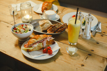 Healthy breakfast with orange juice, croissants, bread and fruit in a cozy wood table with candle light