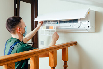 Male technician cleaning air conditioner indoors