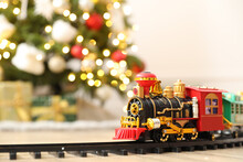 Toy Train And Railway On Floor Against Christmas Lights