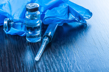 2 doses of Sars-Kov-2 coronavirus vaccine in transparent glass ampoules, covered with frost and a disposable syringe, on a dark background, short focus, toning