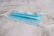 Used surgical face mask isolated on concrete floor