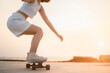 Close-up Asian Beautiful women surf skate or skateboard outdoors on beautiful summer day. Happy young women play surf skate at park near the beach on morning time. Sport activity lifestyle concept.