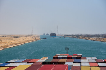 View on the containers loaded on deck of cargo ship. Vessel is transiting Suez Canal on her international trade route. Suez canal landscape.