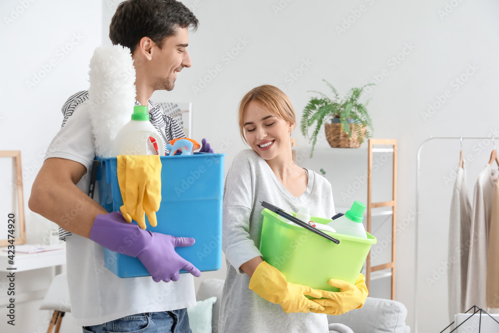 Young couple with cleaning supplies at home