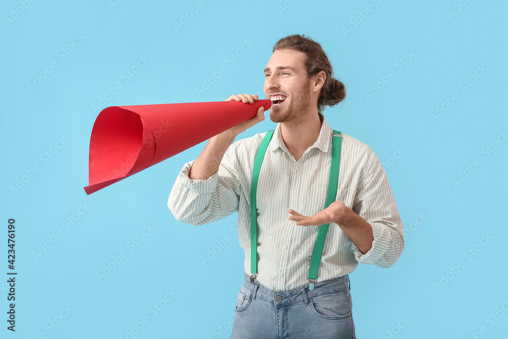 Young man with creative megaphone on color background