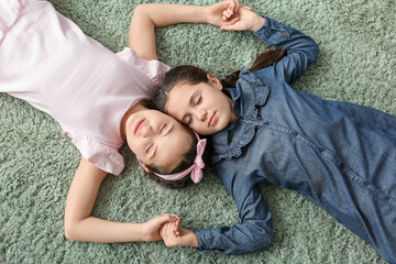 Poster - Portrait of cute twin girls lying on carpet, top view