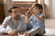 © fizkes - Overjoyed young dad and small 8s son have fun play with animals toys enjoy family weekend at home together. Playful happy Caucasian father engaged in funny game activity with excited little boy child.