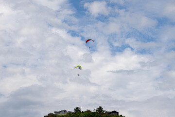 Two para gliders flying on a cloudy day.