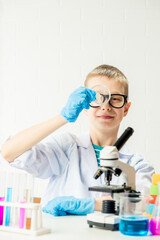Wall Mural - a schoolboy with a microscope examines chemicals in test tubes, conducts experiments - a portrait on