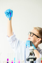 Wall Mural - a schoolboy with a microscope examines chemicals in test tubes, conducts experiments - a portrait on