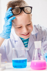 Wall Mural - a schoolboy studies multi-colored substances in test tubes, conducts experiments - a portrait on a w