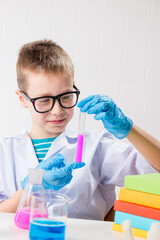 Wall Mural - a schoolboy studies multi-colored substances in test tubes, conducts experiments - a portrait on a w