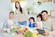 © Friends Stock - Good food makes your day. Hispanic family smiling at camera while enjoying a meal together at home. Middle aged father with little son using tablet pc, sitting at kitchen table