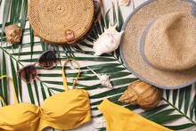 Female Beach Accessories: Swimsuit, Bikini, Rattan Bag, Straw Hat, Shells, Sunglasses, Palm Leaves On Sand Background. Exotic, Tropical Mood. Summer Vacation, Travel Concept. Flat Lay. Copy Space
