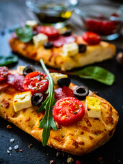 Wall Mural - Focaccia - roasted mozzarella sandwiches with salami pepperoni, feta cheese and tomatoes on black stone plate
