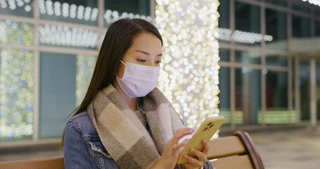 Wall Mural - Woman wear face mask and use of smart phone at night