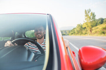 Man with a beard driving a car.