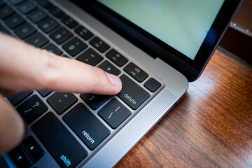 close up of finger pressing on delete button on the laptop computer. delete everything