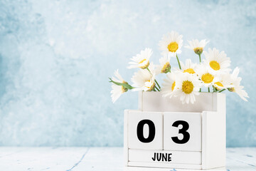 cube calendar for June with daisy flowers over blue