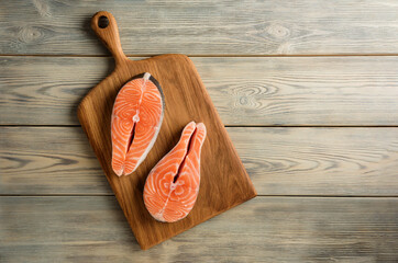 Composition with salmon steaks on the background of a wooden table with copy space.