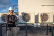 © spatesphoto - HVAC technician standing next to air conditioners outside