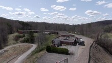 Aerial Drone Footage Dollying Forward Over A Creepy Abandoned Hotel On Top Of A Hill.  Windy Overgrown Road, Broken Sign, Vandalized And Decayed.