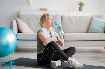Wall Mural - Wellness concept. Fit mature lady drinking fresh clear water from bottle after sports workout at home, copy space