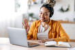 © Kateryna - Friendly young attractive African American woman in headset, call center employee, support operator, working at a laptop, conducts online consultation with customer, looking at the screen, smiling