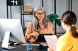 © Kateryna - Intelligent confident influential gray-haired female asian wearing glasses, business lady, HR manager, talking to job candidate in modern office, holds and studies resume, smiling friendly