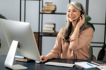 Joyful Successful Beautiful Mature Asian Business Woman Call Center Manager Working In Office, Communicating With Business Team Via Virtual Conference, Video Call, Using Headset, Smiling Friendly