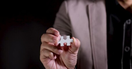 Poster - Slow Motion 4K Video close up businessman show jigsaw piece in hand. Concept for business strategy and marketing plan.