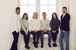 © Studio Romantic - Happy young multiracial people standing by the window or sitting on windowsill, smiling and looking at camera. Group portrait of successful business startup team, fellow students, friends or coworkers