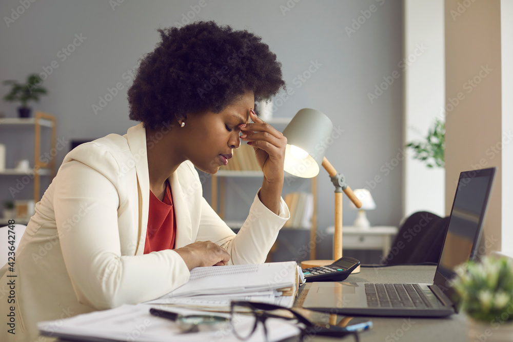 Feeling tired and stressed, workload, burnout and fatigue. Frustrated young african american woman keeping eyes closed and massaging nose after working at laptop for long time in office - obrazy, fototapety, plakaty 