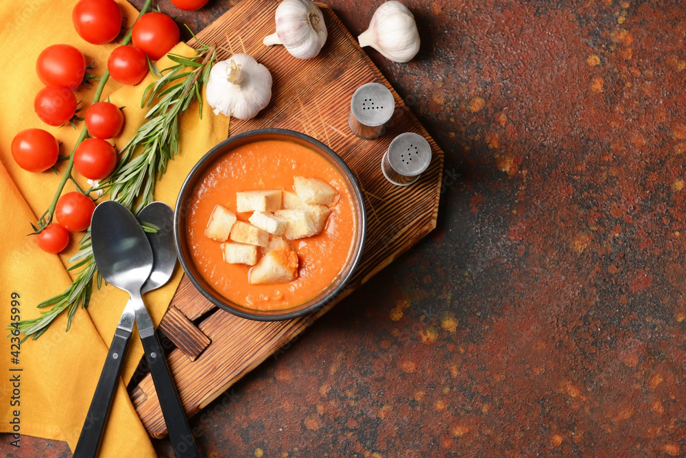 Bowl with tasty tomato cream soup on grunge background