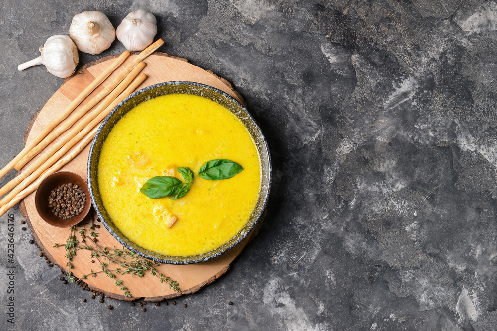 Plate with tasty garlic cream soup on dark background