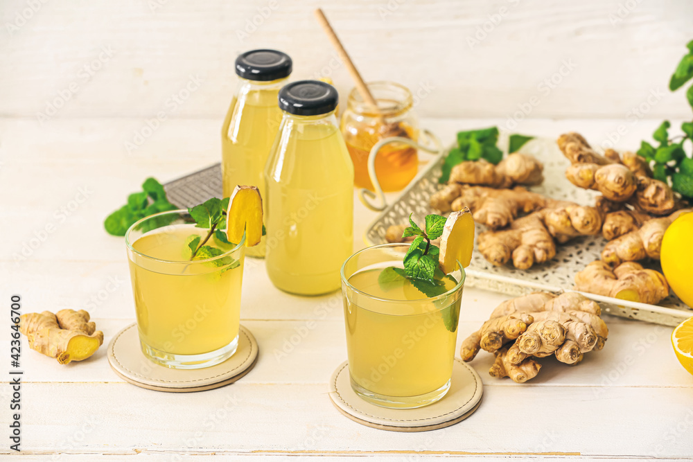 Composition with healthy ginger juice on light wooden background