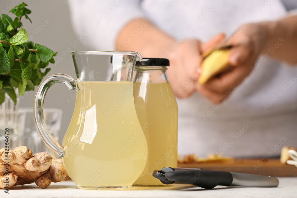 Jug and bottle of healthy ginger juice on table