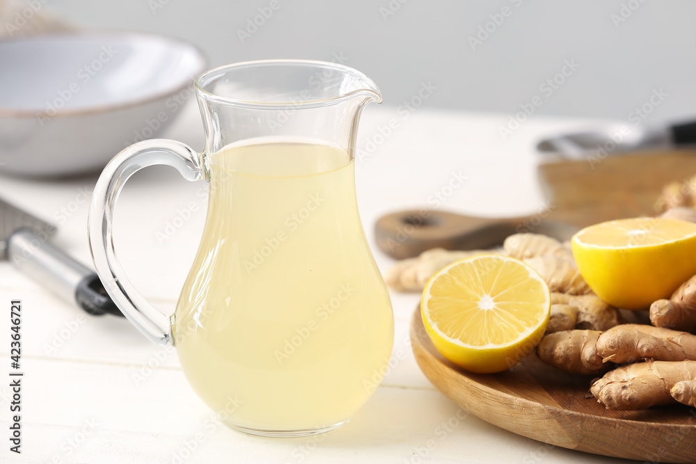 Glass jug of healthy ginger juice on table