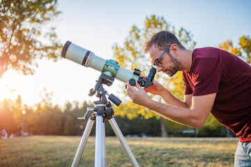 Wall Mural - amateur astronomer looking at the sky with a telescope.