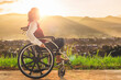 Disabled handicapped woman sitting on wheelchair sunset background. International Disability Day.