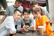 © imtmphoto - group of young asian adults looking at cellphone together