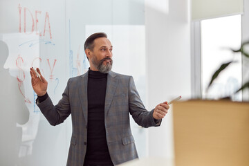 Wall Mural - Caucasian adult man in office is writing on the glass desk