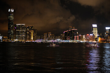 Wall Mural - Night panorama of Hong Kong harbor and Kowloon side with illuminated skyscrapers and city lights reflecting on water