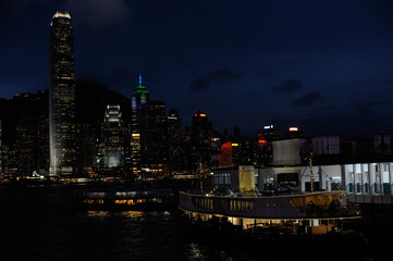 Wall Mural - Night panorama of Hong Kong harbor and Victoria side financial center with illuminated skyscrapers and city lights reflecting on water