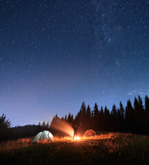 Wall Mural - male traveler standing near campfire and pointing at stars.