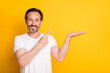 © deagreez - Photo of happy cheerful mature man point finger hold hand empty space advert isolated on yellow color background